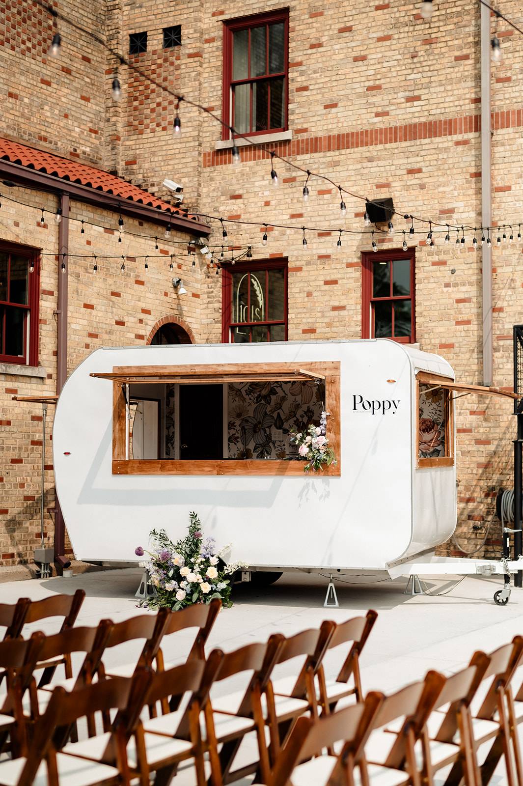 Poppy, the vintage white camper bar, set up in the courtyard at 10 South wedding venue in Janesville, WI