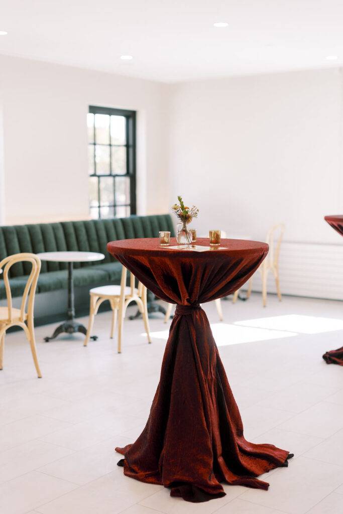 Velvet cocktail table with floral bud vase and candles in front of green banquette seating at 10 South in Janesville, WI