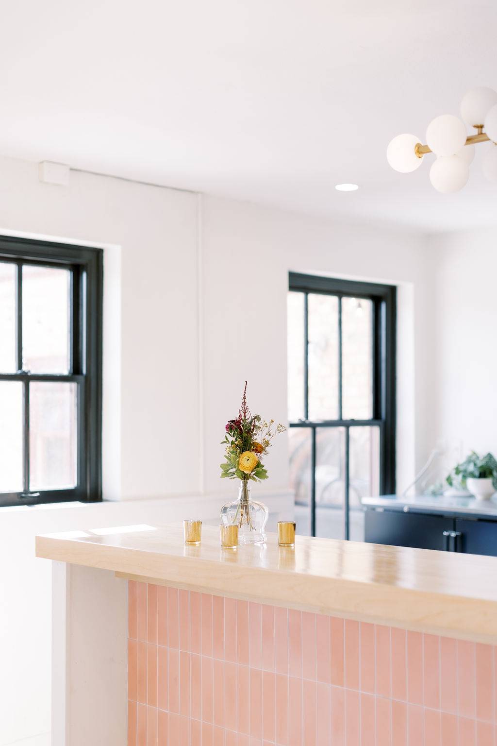Close-up of pink tile indoor wedding bar with floral bud vase and votive candles at 10 South in Janesville, WI