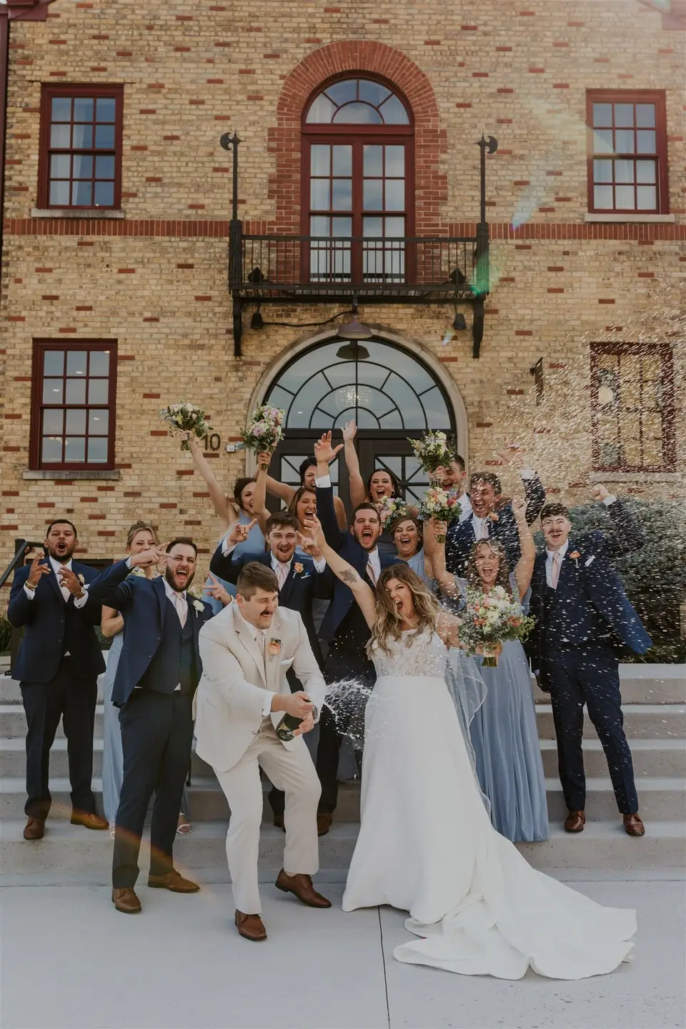 Wedding party celebrating with champagne pop outside 10 South wedding venue in Janesville, WI
