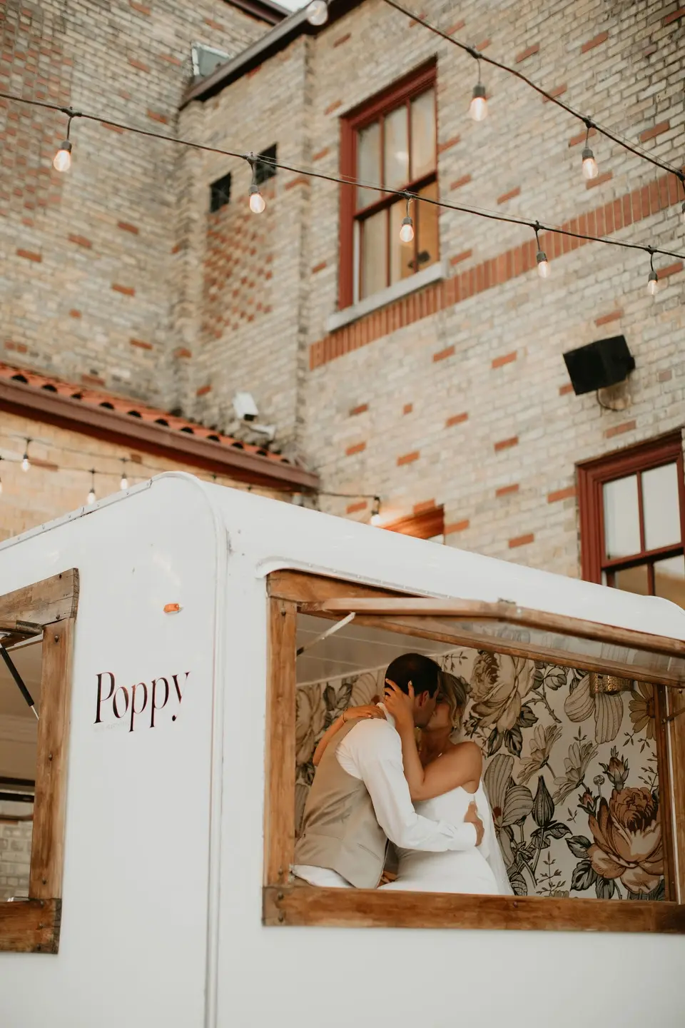 Bride and groom share a kiss inside Poppy the mobile camper bar at 10 South wedding venue in Janesville, WI