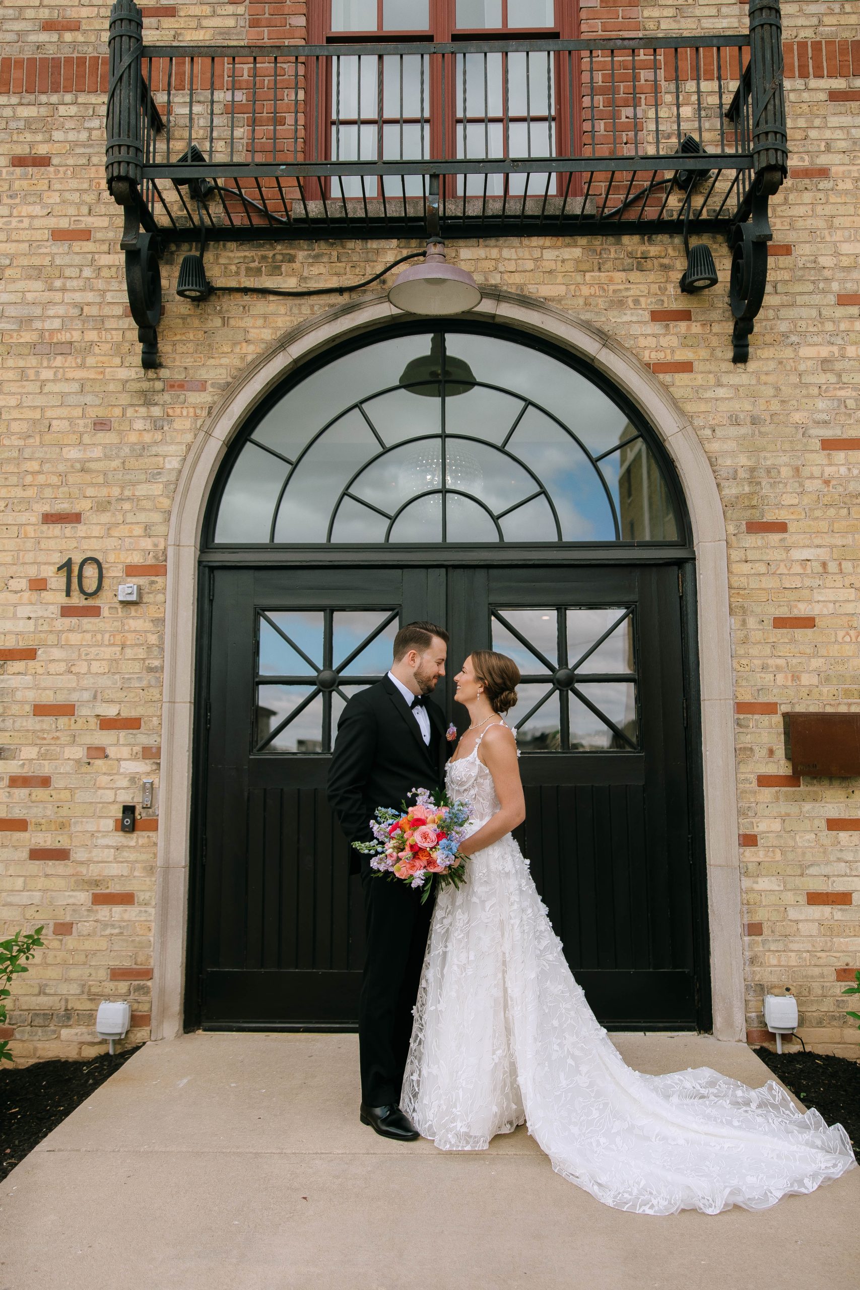 Bride and groom share a quiet moment outside 10 South beneath the arched black doors and historic brick facade.