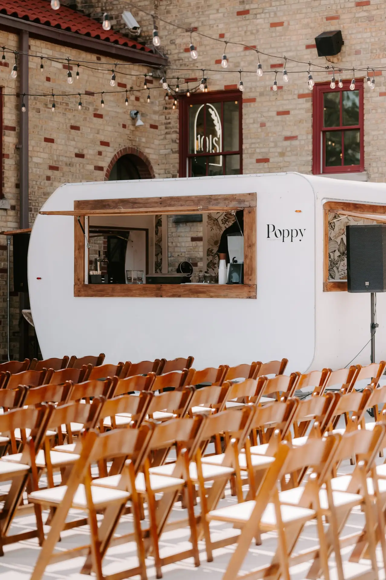 Poppy, a vintage camper bar, set up behind rows of ceremony chairs at 10 South wedding venue in Janesville, Wisconsin