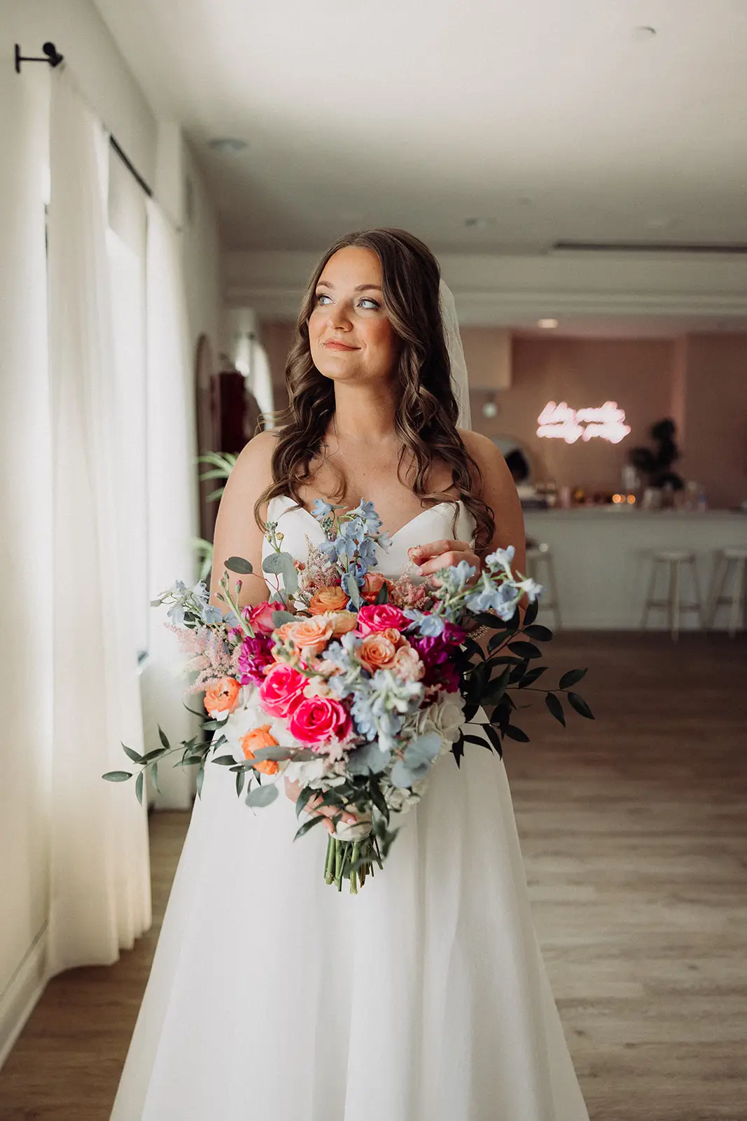 Bride holding vibrant bouquet stands in 10 South’s modern indoor bar and lounge space in Janesville, WI