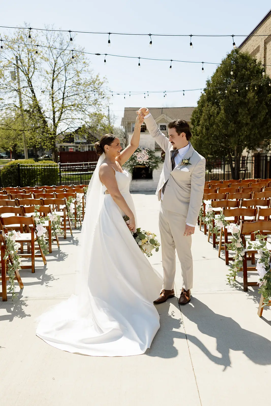 Bride and groom share a joyful twirl during their outdoor wedding ceremony at 10 South in Janesville, WI