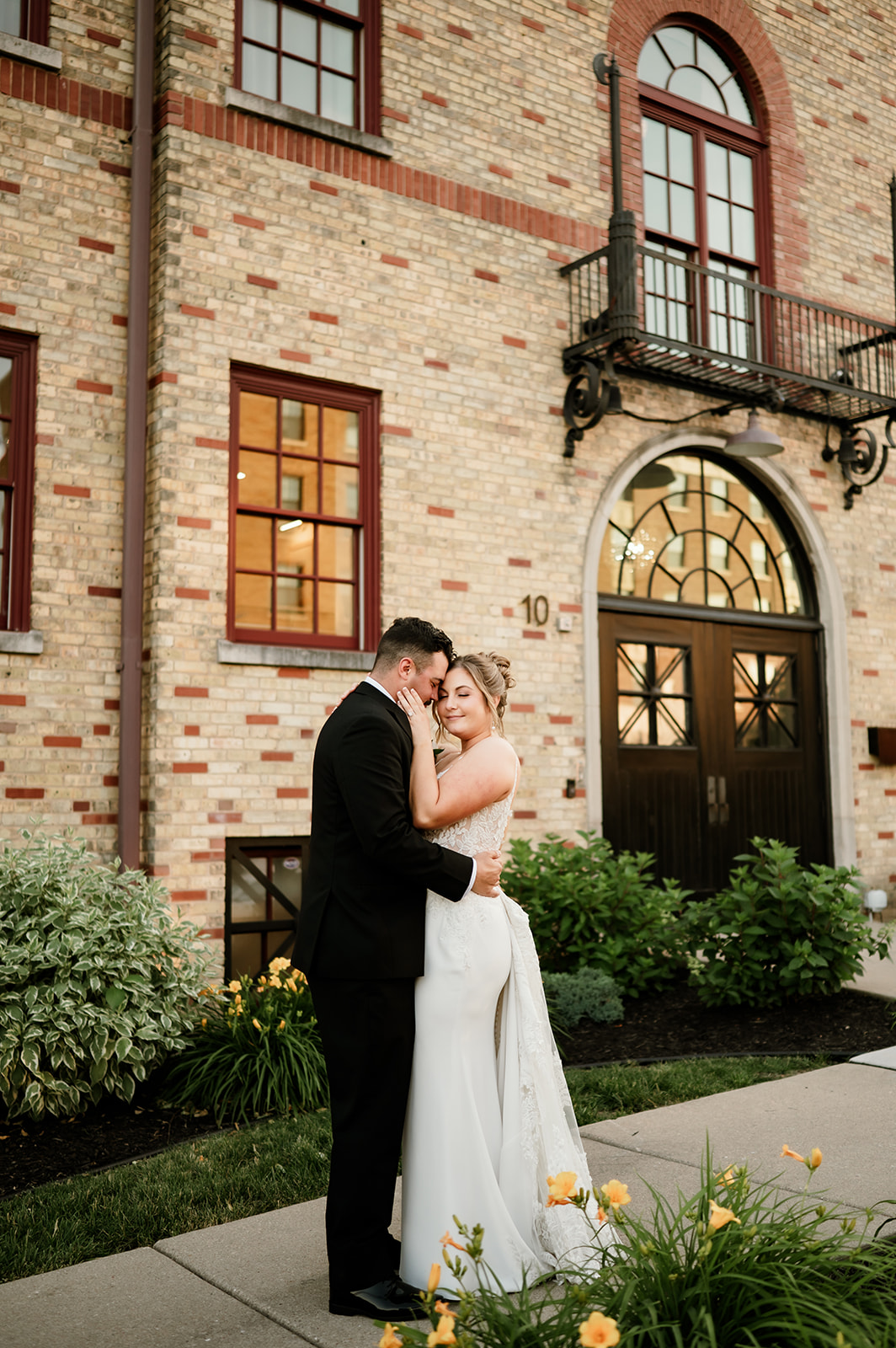 Bride and groom share an intimate embrace in front of the arched entrance at 10 South.